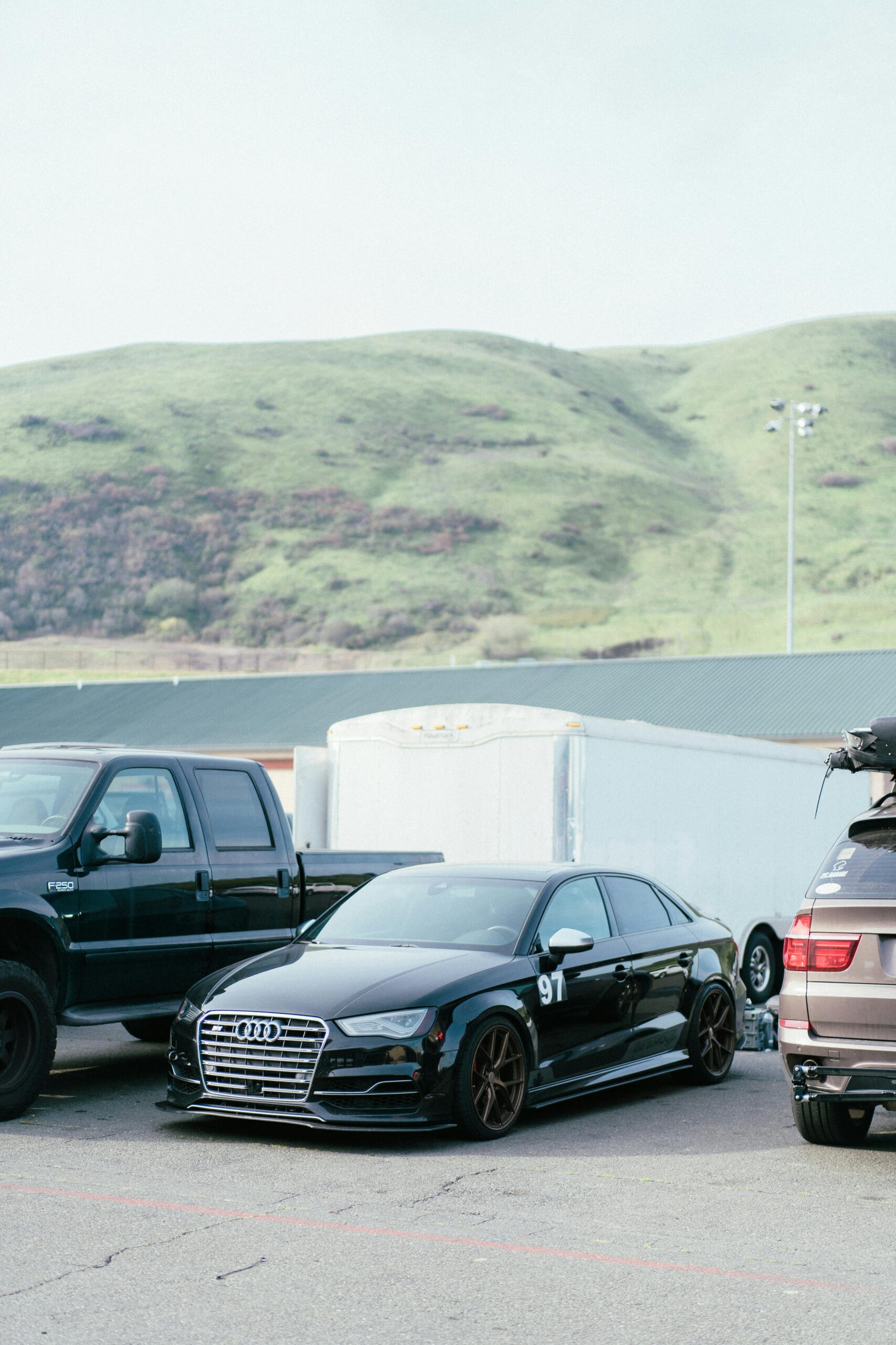 Black luxury car parked with hills in the backdrop at Sonoma Raceway.